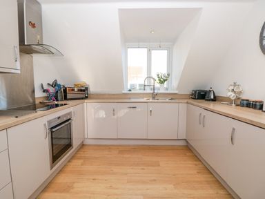 A kitchen with light wood countertops white cabinets a stove an oven a sink a toaster a kettle and utensils at Seaspray Stoke Fleming Near Dartmouth