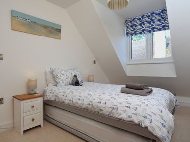 A bedroom with a single bed bedside table with lamp and a window with patterned blind at Seaspray in Stoke Fleming Near Dartmouth