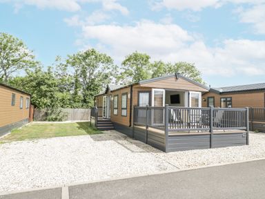 A mobile home with a porch and decking in a gravel area at Serendipity