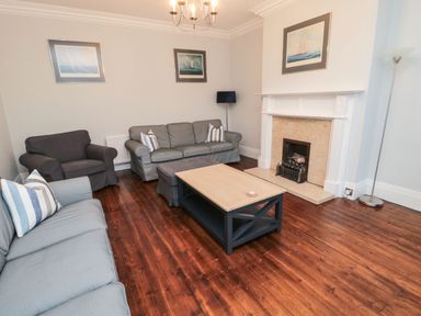 A living room with sofas a coffee table a fireplace and framed pictures on the wall at Glenander in Bamburgh