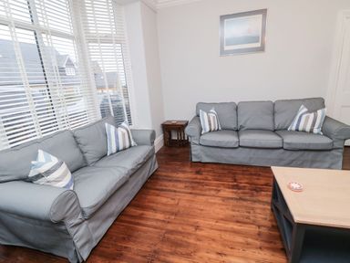 A living room with two gray sofas striped pillows wooden floor and a coffee table at Glenander in Bamburgh