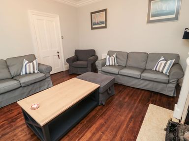 A living room with gray sofas a wooden coffee table and hardwood floor at Glenander in Bamburgh