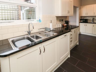 A kitchen with a double sink dish rack and countertop appliances at Glenander in Bamburgh
