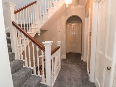 A hallway with carpeted stairs and multiple doors at Glenander in Bamburgh
