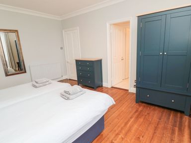 A bedroom with two beds folded towels wardrobe and chest of drawers at Glenander in Bamburgh