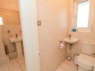 A bathroom with a toilet sink and window at Glenander in Bamburgh