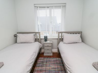 A bedroom with two single beds and a small bedside table with a lamp between at Glenander in Bamburgh