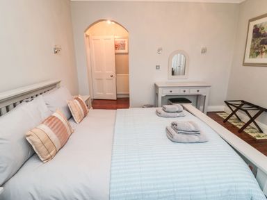 A bedroom with a bed with pillows and towels a dressing table and a luggage rack at Glenander in Bamburgh