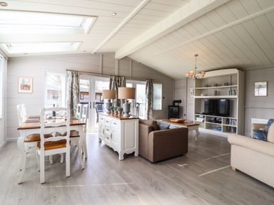 A living room and dining area with white wooden furniture and two sofas at Skylarks in Fornham St Genevieve near Bury St Edmunds