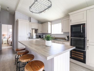 A kitchen with an island and wooden stools and appliances at Skylarks in Fornham St Genevieve near Bury St Edmunds