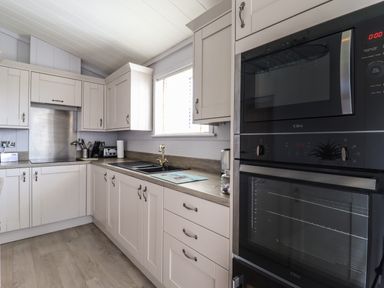 A kitchen with light cabinets a countertop a sink a window and built in ovens at Skylarks in Fornham St Genevieve near Bury St Edmunds