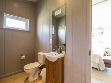 A bathroom with a toilet sink mirror and window at Skylarks in Fornham St Genevieve near Bury St Edmunds