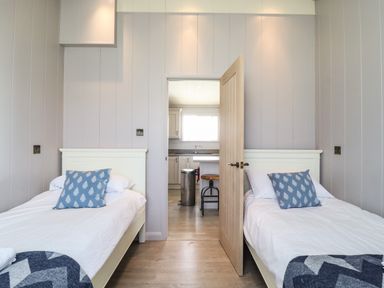 A bedroom with two single beds and blue pillows between rooms at Skylarks in Fornham St Genevieve near Bury St Edmunds