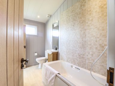 A bathroom with a bathtub a toilet a sink with a mirror and a window at Skylarks in Fornham St Genevieve near Bury St Edmunds