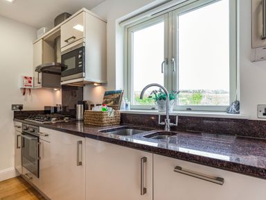 A kitchen with a gas stove oven microwave sink window and countertop at Constantine Bay Cottage in Constantine Bay
