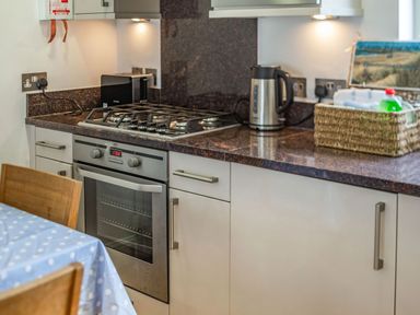 A kitchen counter with a gas stove oven kettle toaster and a basket on the countertop at Constantine Bay Cottage in Constantine Bay
