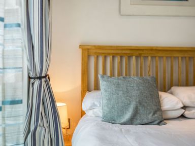 A bedroom with a wooden bed frame pillows and a bedside lamp at Constantine Bay Cottage in Constantine Bay