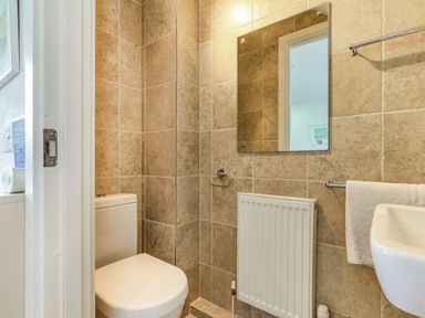A small bathroom with a toilet sink towel radiator and mirror at Constantine Bay Cottage in Constantine Bay