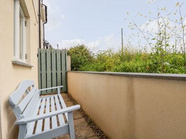 A small outdoor patio area with a bench and a green wooden gate at Constantine Bay Cottage in Constantine Bay