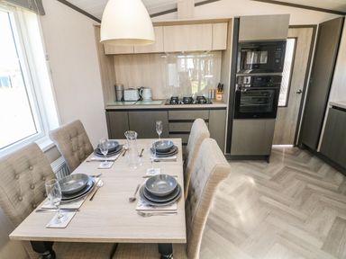 A kitchen and dining area with a set table and modern appliances at Puffin Lodge in Broad Haven