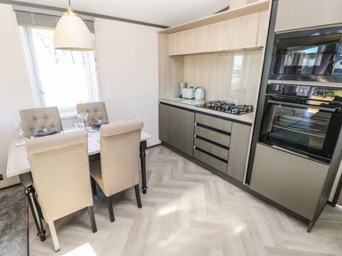 A kitchen with a dining table and four chairs a gas stove and built in oven at Puffin Lodge in Broad Haven