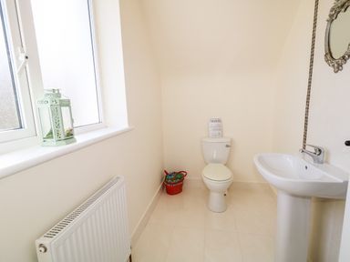 A bathroom with a toilet pedestal sink a window with a lantern and a radiator at Wisteria Cottage in Annagry County Donegal