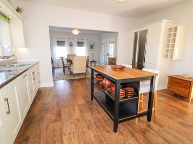A kitchen with an island and wooden bowls next to a dining room with a table and chairs at Wisteria Cottage in Annagry County Donegal