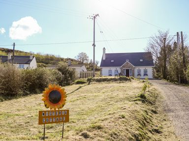 A house with a stone driveway and a sign reading Wisteria Cottage in the front yard at Wisteria Cottage in Annagry County Donegal