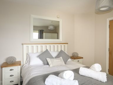 A bedroom with a bed with white and gray pillows and towels on it at 4 Pen Llanw Tides Reach in Rhosneigr