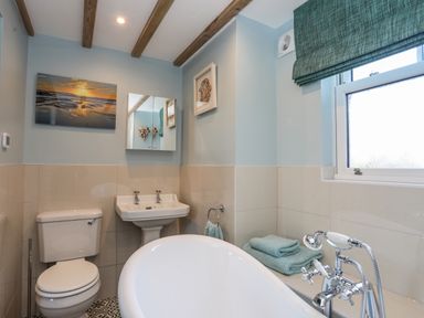 A bathroom with a toilet sink and bathtub with folded towels on the side at Bryn Moelyn Cottage in Yr Efail near Morfa Nefyn