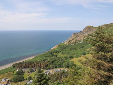 A coastal landscape with a beach parking area and green hills at Bryn Moelyn Cottage in Yr Efail near Morfa Nefyn