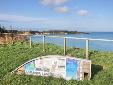 A coastal view with a wooden fence and an informational display about North Dinllaen at Bryn Moelyn Cottage Yr Efail near Morfa Nefyn