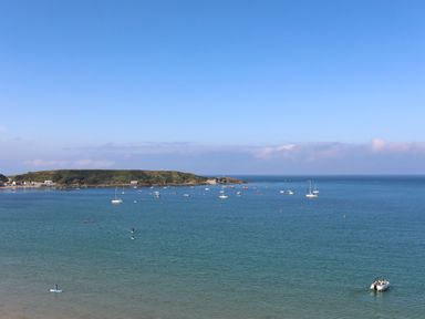 A coastal scene with boats on the water and a green headland in the background at Bryn Moelyn Cottage in Yr Efail near Morfa Nefyn