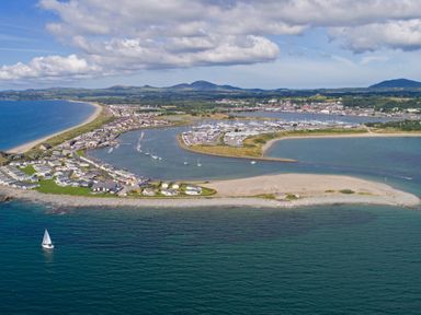 An aerial view of a coastal town with a marina sandy beach and houses along the shoreline at Bryn Moelyn Cottage in Yr Efail near Morfa Nefyn