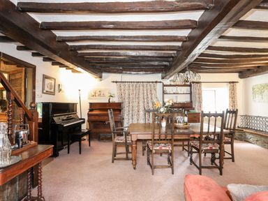 A dining room with wooden table and chairs a black piano and a wooden piano at Gilfachwydd Islawrdref near Dolgellau