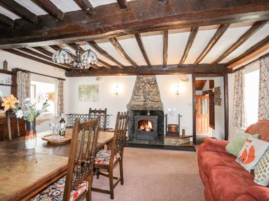 A dining room with wooden table and chairs a fireplace and sofa at Gilfachwydd in Islawrdref near Dolgellau