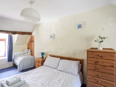 A bedroom with a double bed side table armchair chest of drawers and window at Gilfachwydd in Islawrdref near Dolgellau
