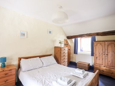 A bedroom with a bed and wooden furniture including a chest of drawers wardrobe and bedside table at Gilfachwydd Islawrdref near Dolgellau