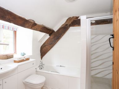 A bathroom with a bathtub toilet shower and exposed wooden beams at Gilfachwydd in Islawrdref near Dolgellau