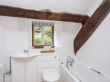 A bathroom with a bathtub sink and toilet under wooden beams at Gilfachwydd Islawrdref near Dolgellau