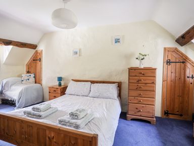 A bedroom with a double bed bedside table with lamp chest of drawers and two wooden doors at Gilfachwydd Islawrdref near Dolgellau