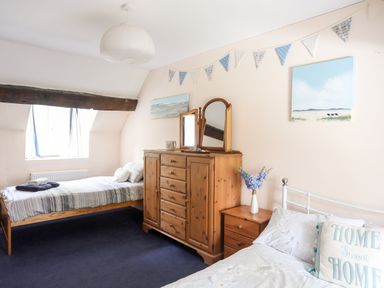 A bedroom with two beds a wooden dresser with mirrors a bedside table with flowers and wall paintings at Gilfachwydd Islawrdref near Dolgellau