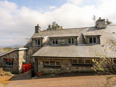 A stone house with multiple windows chimney stacks and red gas cylinders outside at Gilfachwydd Islawrdref near Dolgellau