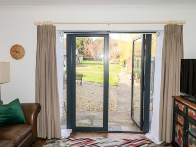 A living room with glass doors opening to a garden at Farriers Retreat in Budleigh Salterton