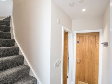 A hallway with carpeted stairs and two wooden doors at Cwm Gwyrfai in Caernarfon