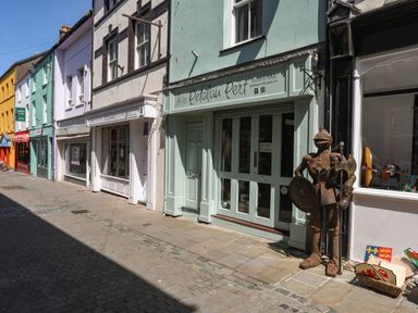 A street with colorful shopfronts and a knight statue outside a shop at Cwm Gwyrfai in Caernarfon
