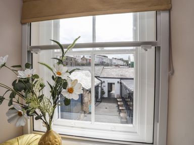 A window view with white flowers in a vase and buildings outside at Moel Tryfan in Caernarfon
