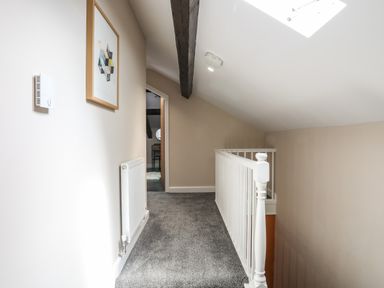 A carpeted hallway with white railing and a wooden beam on the ceiling at Moel Tryfan in Caernarfon