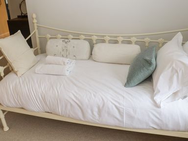 A bed with white sheets and multiple pillows and towels at Manor Cottage Poulton
