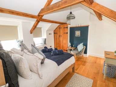 A bedroom with a bed with pillows and rolled towels wooden beams and a wooden floor at 1 Salt Cottage Port Eynon